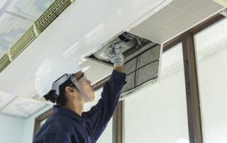 Air conditioner cleaning: man wearing gloves checks the filter, young man adjusting the air conditioning system