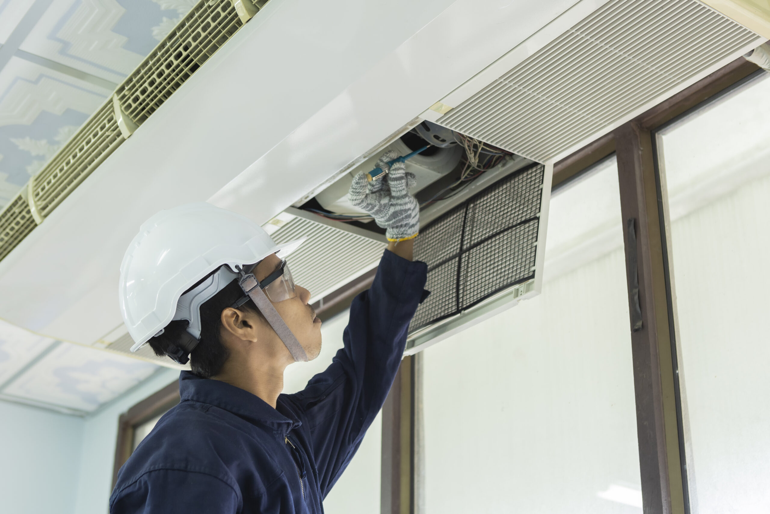 air-conditioner-cleaning-man-gloves-checks-filter-young-man-adjusting-air-conditioning-system Air conditioner cleaning: man wearing gloves checks the filter, young man adjusting the air conditioning system