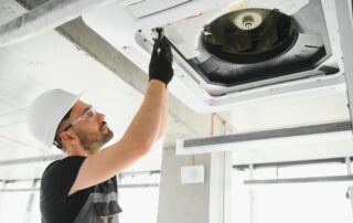 HVAC technician installing and servicing a ceiling air conditioning unit
